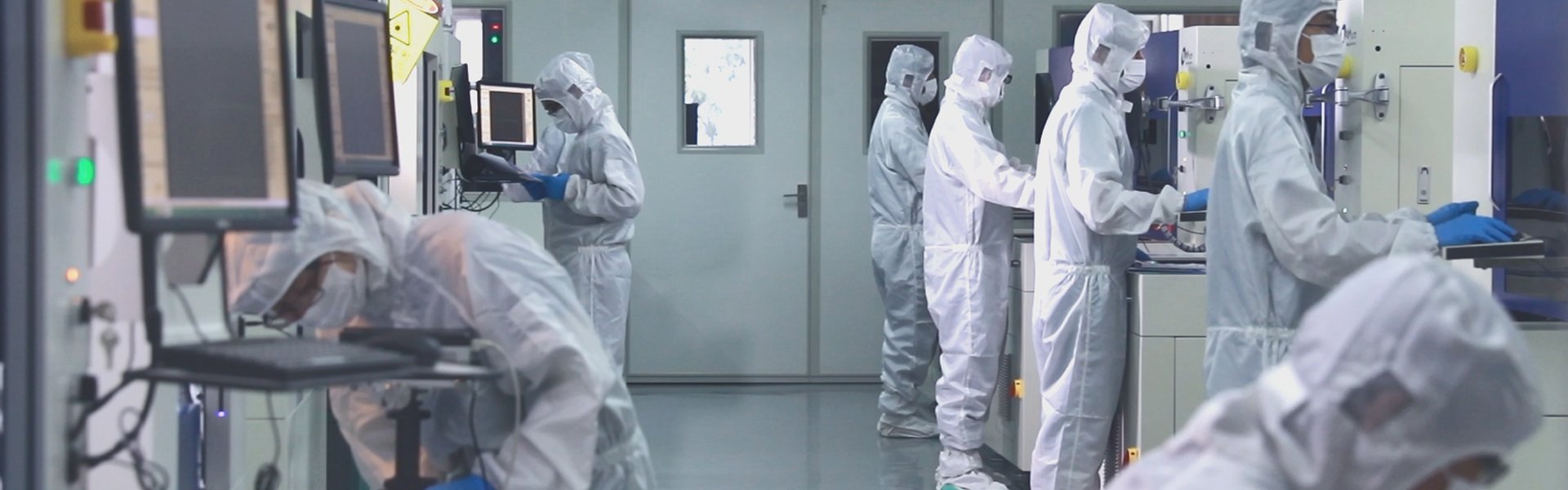 SMT assembly technicians in cleanroom suits operating high-precision PCB manufacturing equipment.